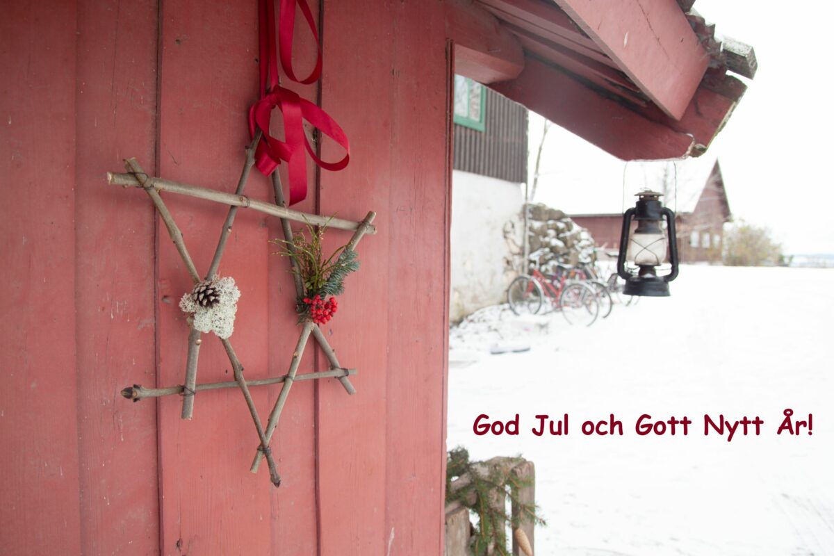 röd stugknut med juldekoration på gård med vit snö