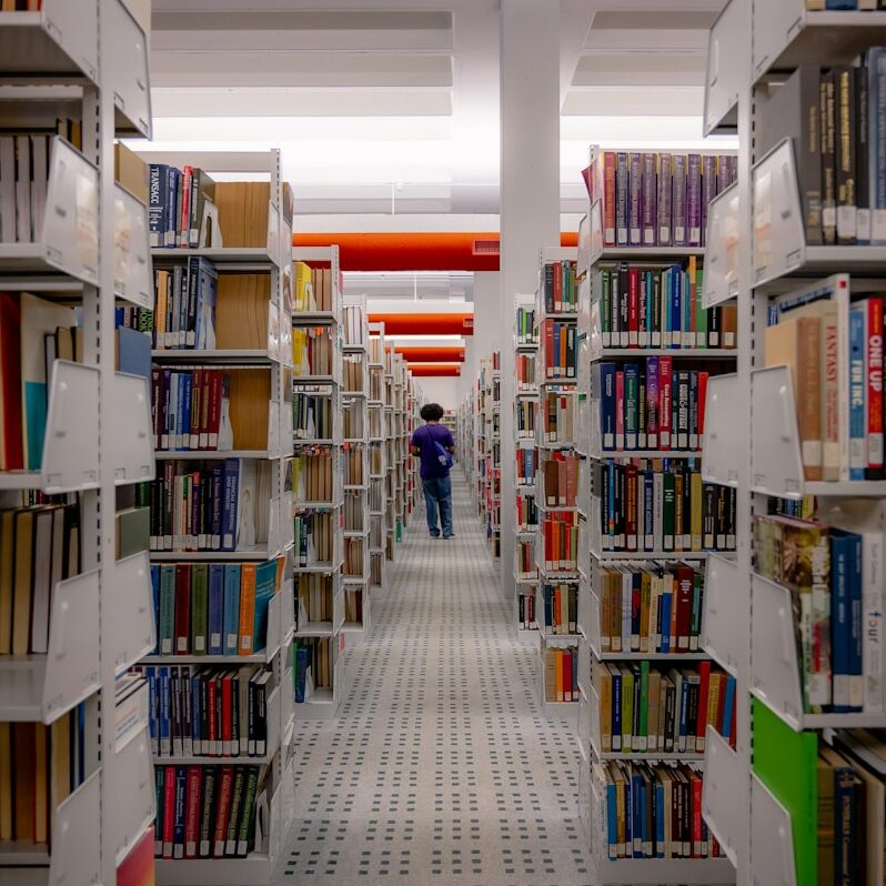a man walking through a library filled with lots of books